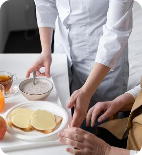 Caregiver preparing a meal for an elderly patient