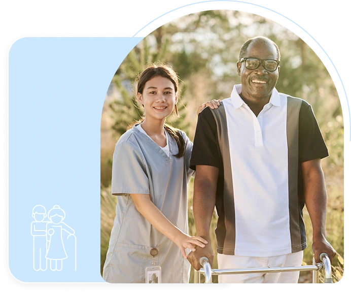 A smiling nurse supports a senior man with a walker outside on a sunny day.