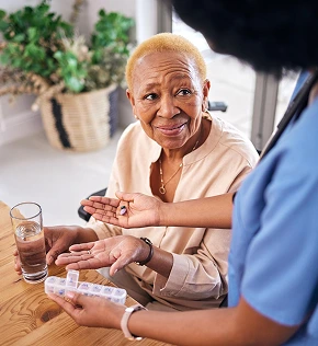 Caregiver helping senior woman organize daily medication during in-home care visit