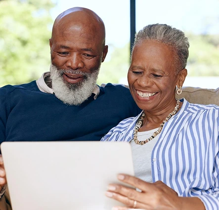Older couple smiling while looking at a laptop together