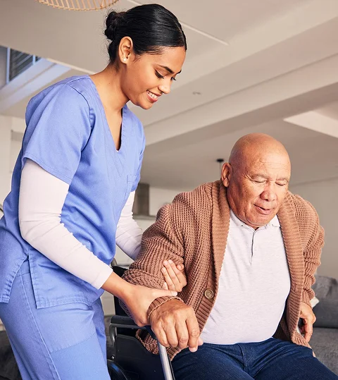 A caregiver helping an elderly man rise from a chair at home