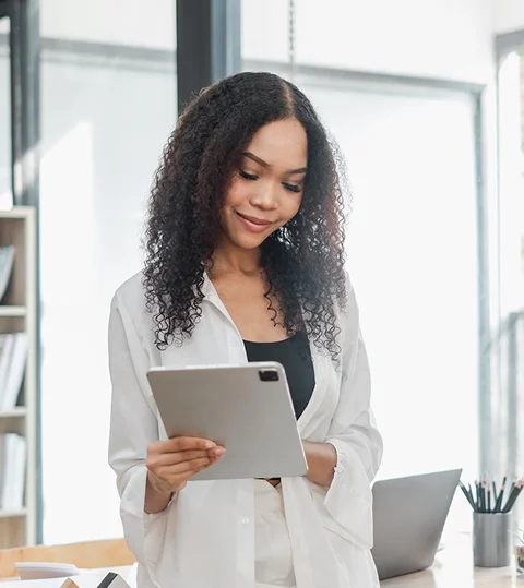 A young professional woman reviewing information on a tablet in an office