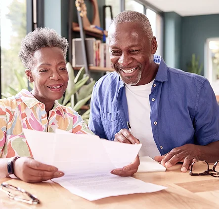 A senior couple smiling and reviewing documents together at a table